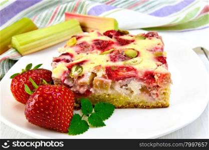 Piece of pie with strawberries, rhubarb and cream sauce, strawberry, mint in white plate, napkin on a wooden boards background