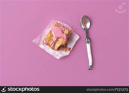 Piece of pink brownie dessert eaten with a spoon on a pink background. Minimal image of eating ruby chocolate cake. Above view of pink dessert.