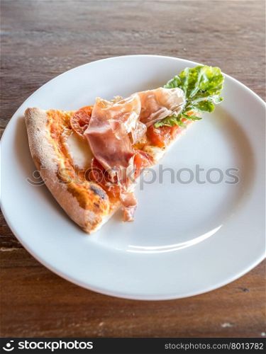 piece of pizza parma ham and rocket salad