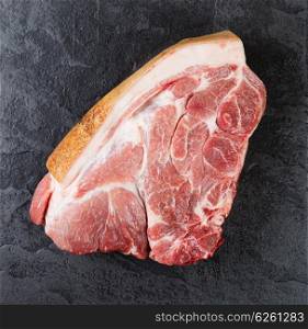 Piece of pork meat on the black stone table