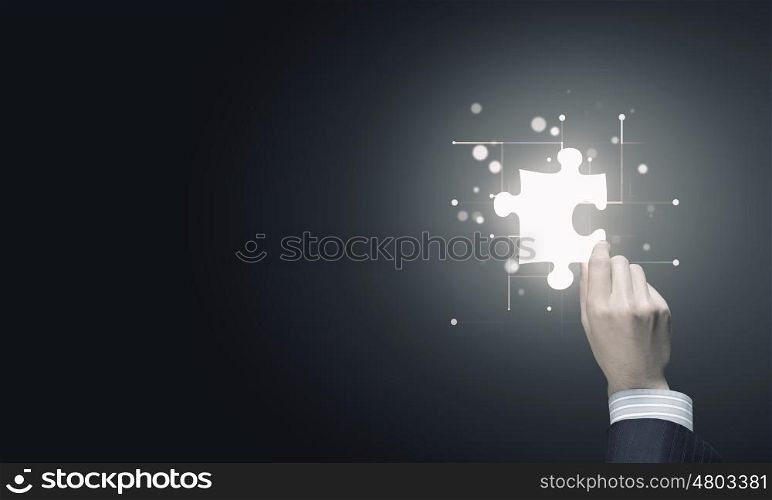 Piece of puzzle. Close up of businessman hand holding glowing jigsaw element