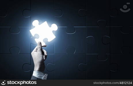 Piece of puzzle. Close up of businessman hand holding glowing jigsaw element