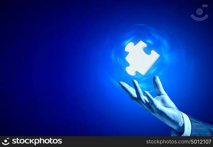 Piece of puzzle. Close up of businessman hand holding glowing jigsaw element