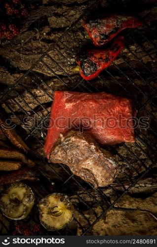 piece of raw meat with vegetables on the grill on a background of tree bark. dish on a tree bark