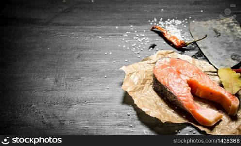 piece of raw salmon with spice and olive oil. On the black chalkboard.. piece of raw salmon with spice and olive oil.