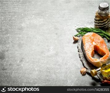 piece of raw salmon with spices and herbs. On a stone background.. piece of raw salmon with spices and herbs. .