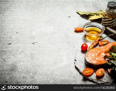 piece of raw trout and tomatoes. On a stone background.. piece of raw trout and tomatoes.