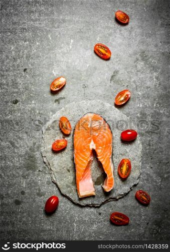 piece of raw trout and tomatoes. On a stone background.. piece of trout and tomatoes.