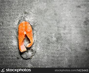 piece of raw trout with salt. On a stone background.. piece of raw trout with salt.