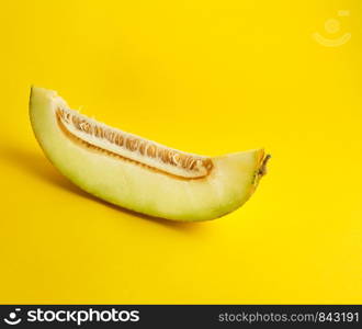 piece of ripe melon with seeds on a yellow background, copy space