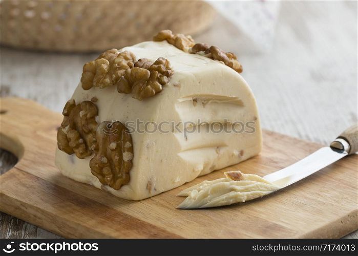 Piece of soft walnut cheese on a cutting board close up