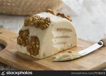 Piece of soft walnut cheese on a cutting board close up