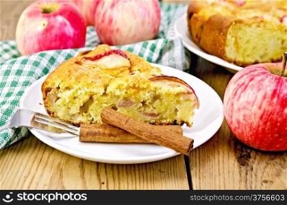 Piece of sweet apple pie, cinnamon, napkin, fork on the background of wooden boards