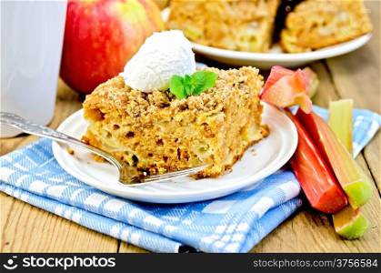 Piece of sweet cake with rhubarb, apples and a scoop of ice cream, mint, napkin, cup on the background of wooden boards