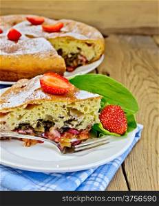 Piece of sweet cake with strawberries and sorrel, napkin, fork on the background of wooden boards