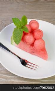 piece of watermelon with watermelon balls and mint on a plate