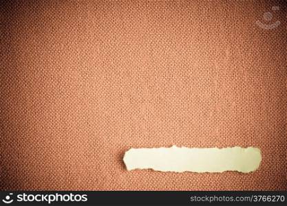 Piece scrap of white paper blank copy space on brown beige fabric textile material background
