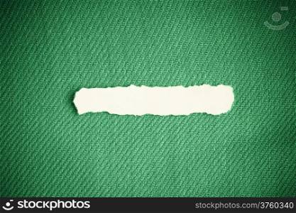 Piece scrap of white torn or ripped paper banner, blank copy space for text message on green fabric textile material background