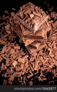 Pieces and grated dark chocolate. On a black background.. Pieces and grated dark chocolate.