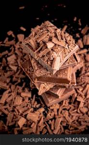 Pieces and grated dark chocolate. On a black background.. Pieces and grated dark chocolate.