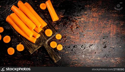 Pieces and whole fresh carrots on a cutting board. Against a dark background. High quality photo. Pieces and whole fresh carrots on a cutting board.