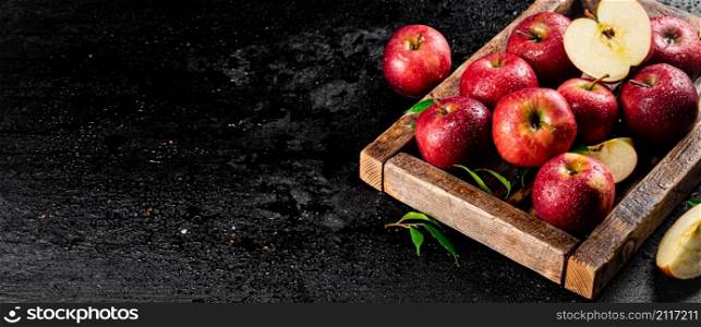 Pieces and whole red apples on a wooden tray. On a black background. High quality photo. Pieces and whole red apples on a wooden tray.