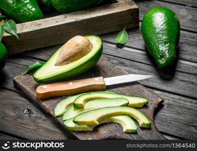 Pieces of avocado and avocado on a dressing. On a black wooden background.. Pieces of avocado and avocado on a dressing.