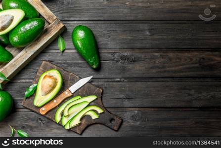 Pieces of avocado and avocado on a dressing. On a black wooden background.. Pieces of avocado and avocado on a dressing.