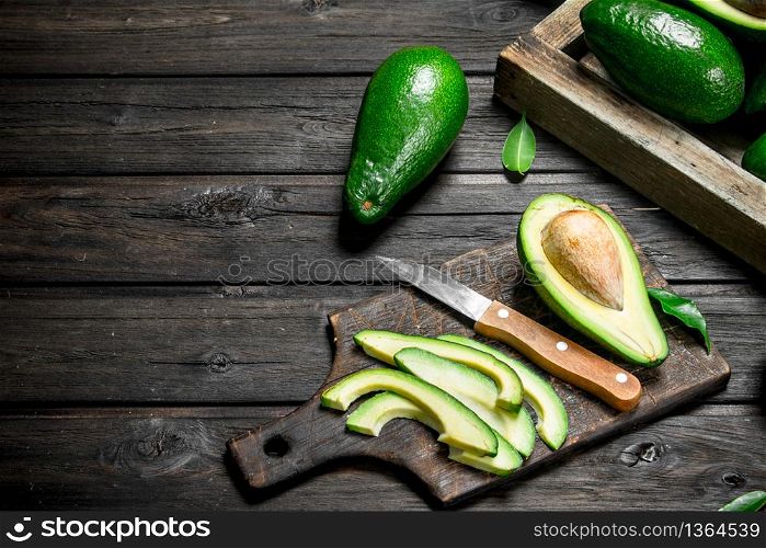 Pieces of avocado on a chopping Board. On a wooden background.. Pieces of avocado on a chopping Board.