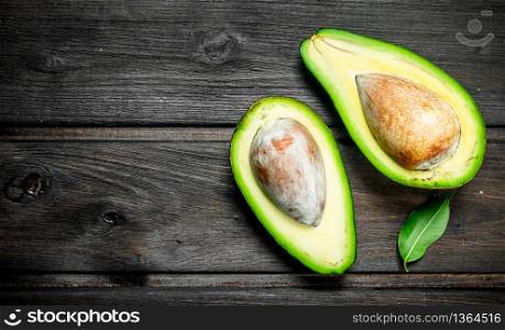 Pieces of avocado with a bone. On a black wooden background.. Pieces of avocado with a bone.