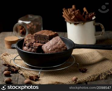 pieces of baked brownie in a metal black frying pan on the table