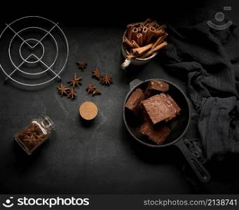 pieces of baked brownie in a metal black frying pan on the table, top view