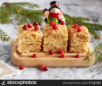 pieces of baked layer of cake Napoleon with butter cream on a wooden board, close up