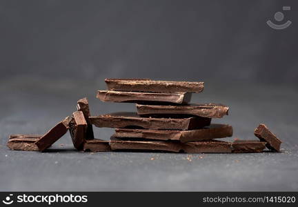 pieces of black chocolate on a black background, sweet dessert, close up