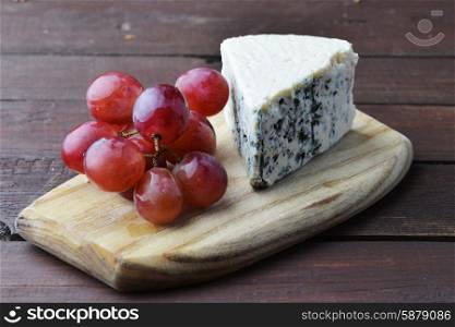 pieces of blue cheese and red grapes on a wooden table