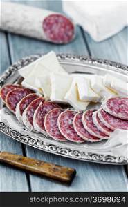 Pieces of brie cheese and air dried salami on a tray. Brie cheese and air dried salami