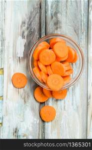 Pieces of carrots in a glass bowl. On wooden background. Pieces of carrots in a glass bowl.