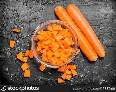 Pieces of carrots on a bowl. On black rustic background. Pieces of carrots on a bowl.