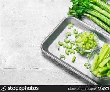 Pieces of celery in a bowl on a tray. On white rustic background. Pieces of celery in a bowl on a tray.