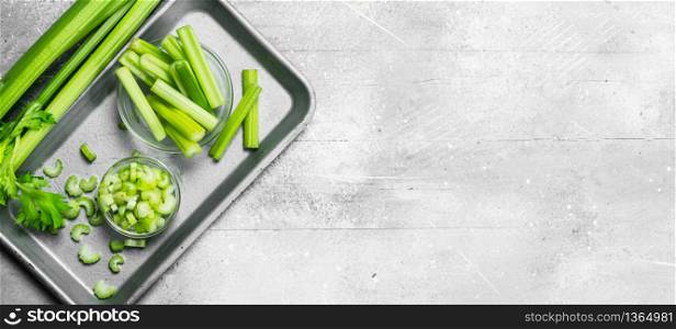 Pieces of celery in a bowl on a tray. On white rustic background. Pieces of celery in a bowl on a tray.