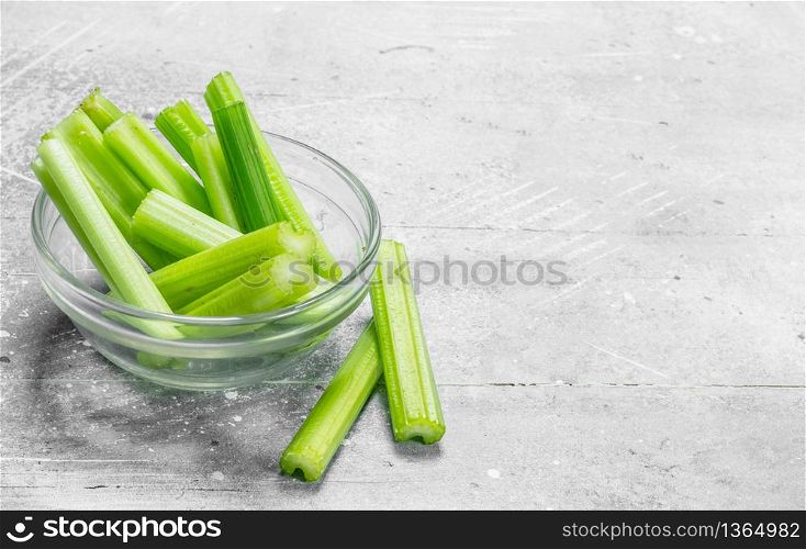 Pieces of celery in a glass bowl. On white rustic background. Pieces of celery in a glass bowl.