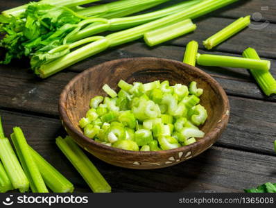 Pieces of celery in a wooden bowl. On black wooden background. Pieces of celery in a wooden bowl.