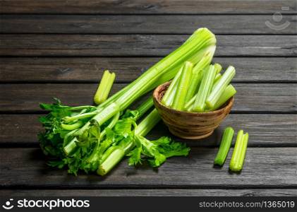 Pieces of celery in a wooden bowl. On black wooden background. Pieces of celery in a wooden bowl.