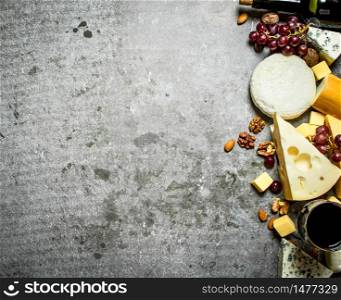 Pieces of cheese with red wine and nuts. On the stone table.. Pieces of cheese with red wine and nuts.