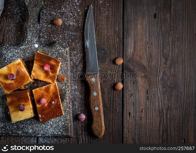 pieces of cheesecake with pumpkin on brown wooden cutting board, empty space