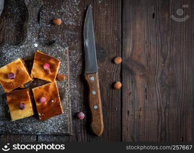 pieces of cheesecake with pumpkin on brown wooden cutting board, empty space