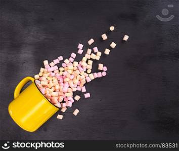pieces of colored marshmallow scattered from a yellow mug, empty space