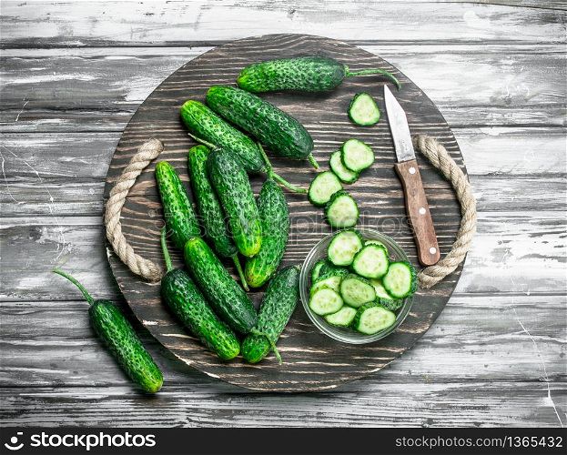Pieces of cucumbers in a bowl on a cutting Board with a knife. On wooden background. Pieces of cucumbers in a bowl on a cutting Board with a knife.