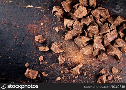 Pieces of dark chocolate on the table. On a black background. . Pieces of dark chocolate on the table.