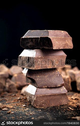 Pieces of dark chocolate on the table. On a black background. . Pieces of dark chocolate on the table.
